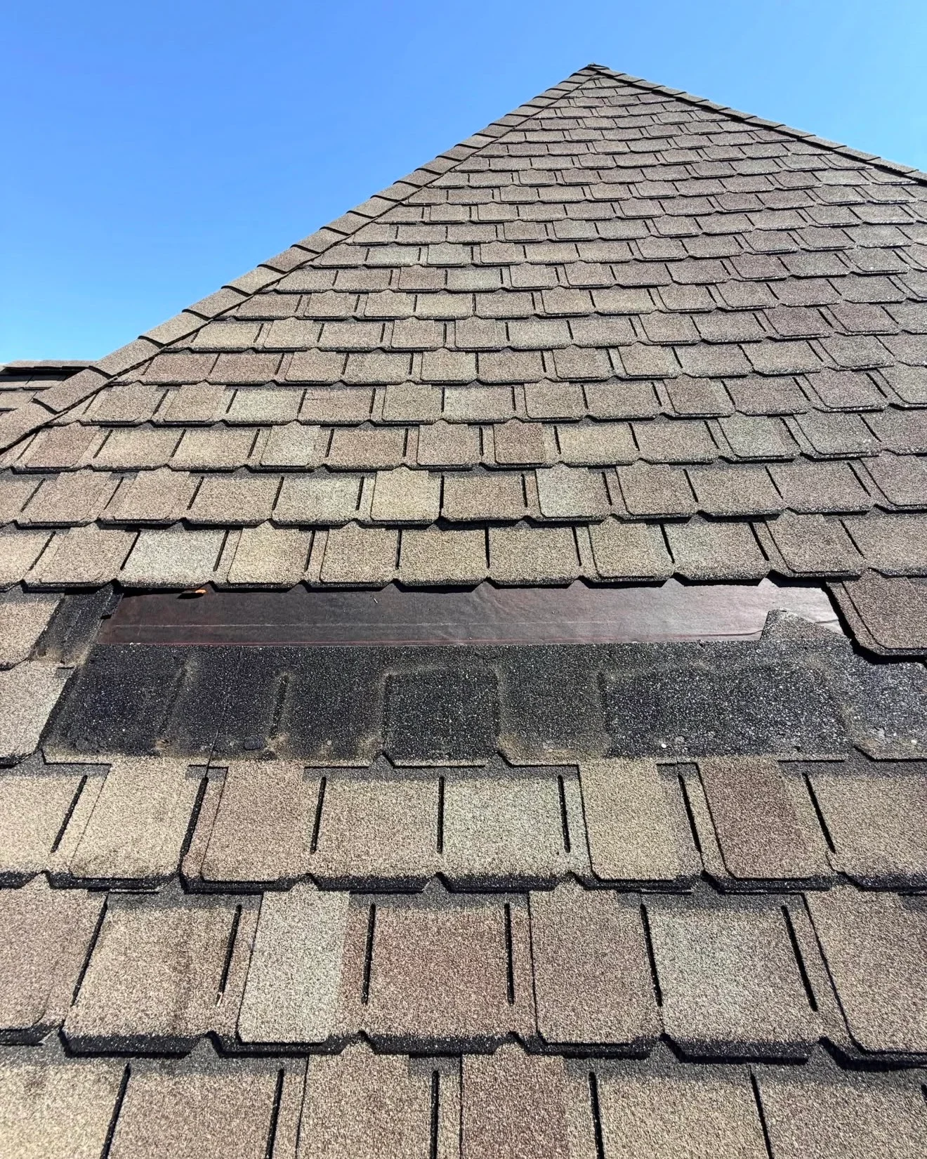 Missing asphalt shingles exposing a horizontal strip of roof underlayment