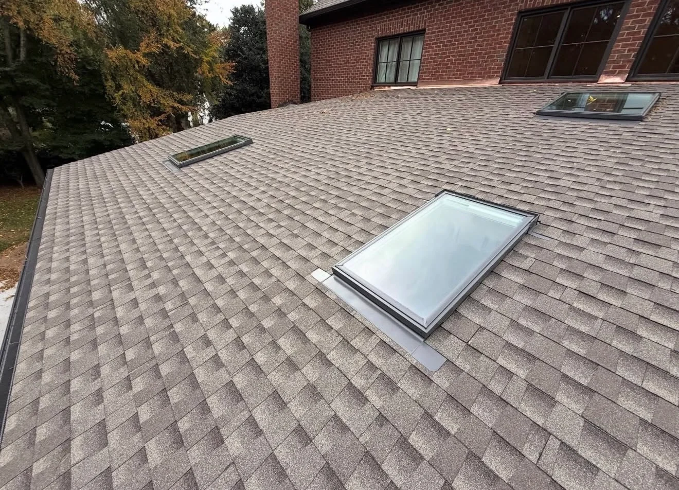Three skylights with metal perimeter flashing on a pitched asphalt-shingle roof