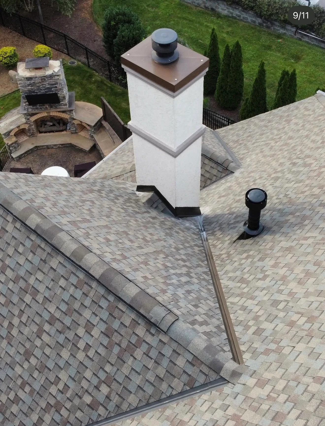 White chimney with dark base flashing and a shingled cricket between intersecting asphalt roof planes