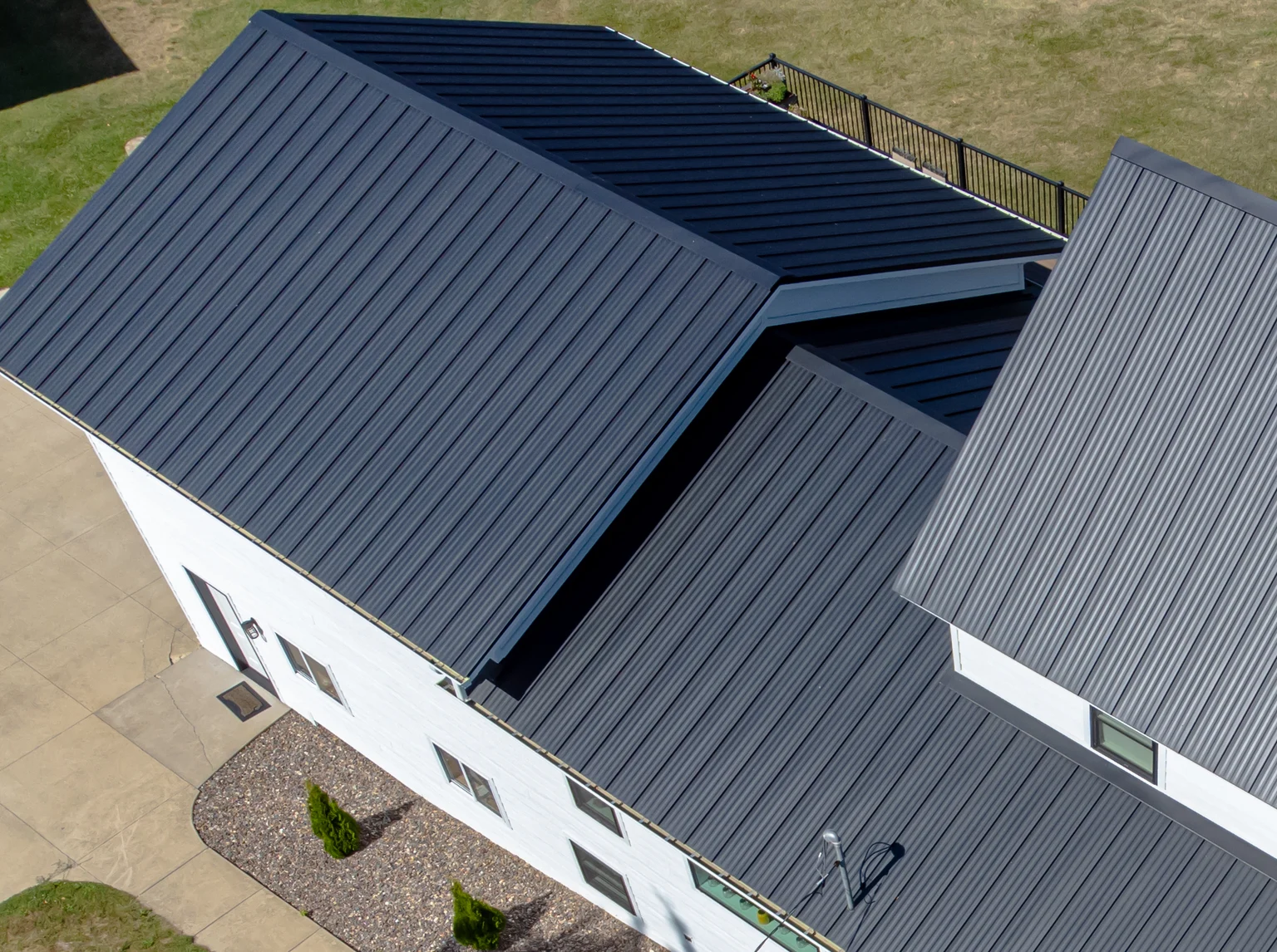 Close-up of black standing-seam panels, ridge and adjoining roof planes on the same home