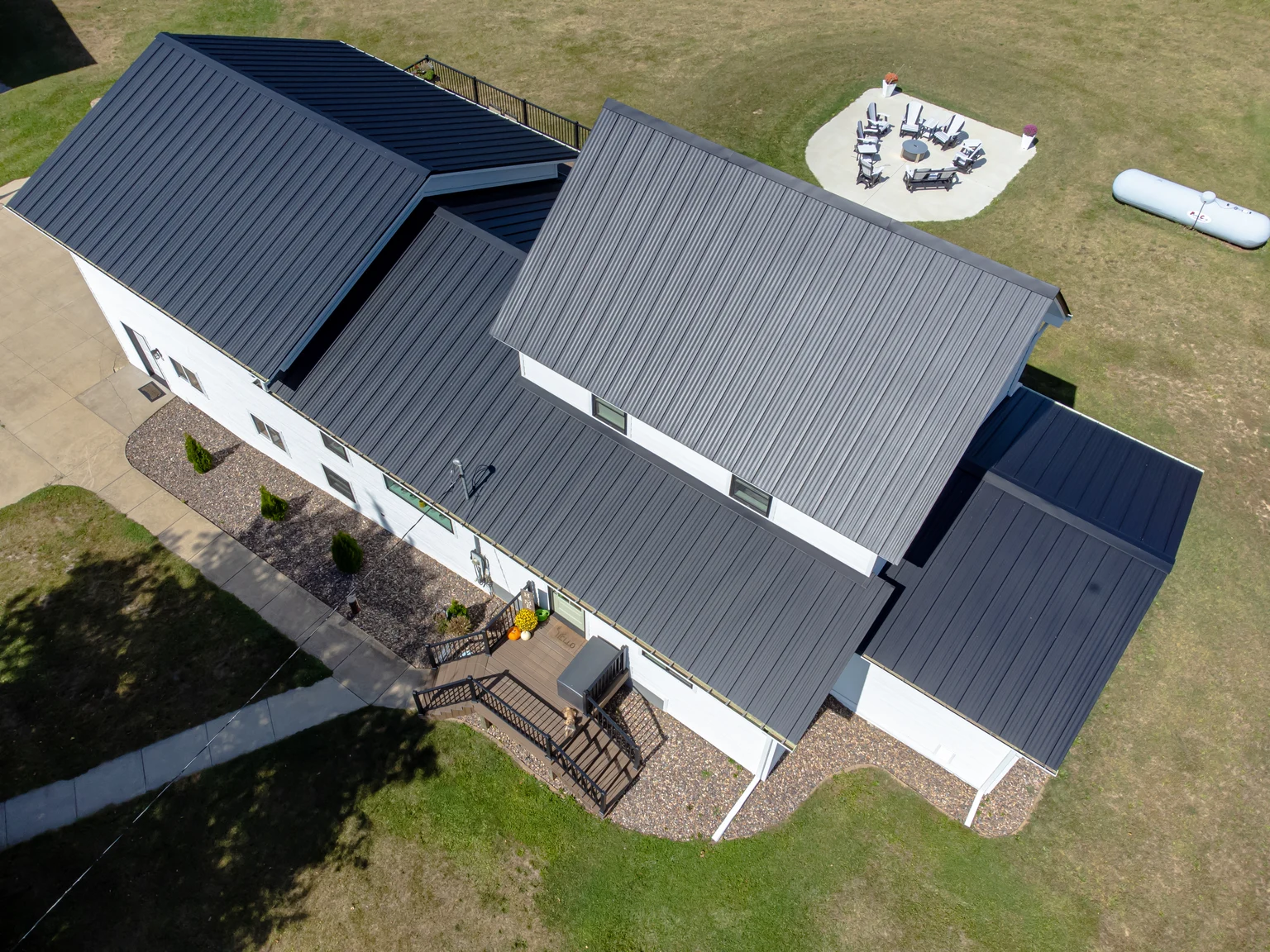 Black standing-seam metal roof on a finished white home, viewed from above